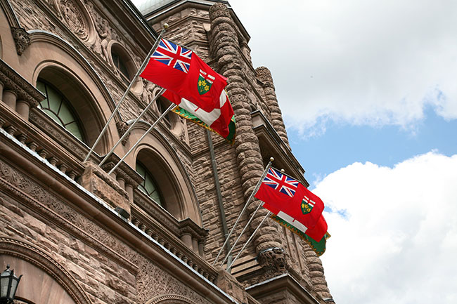 two Ontario flags flying in front of the Legislative Building