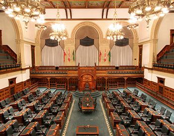 Chambre législative avec bureaux vides, table des greffiers et chaise du président