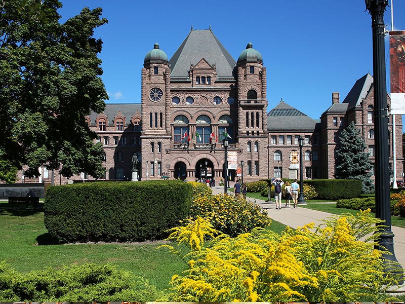 front lawn of Legislative Assembly with trees and buildings in background