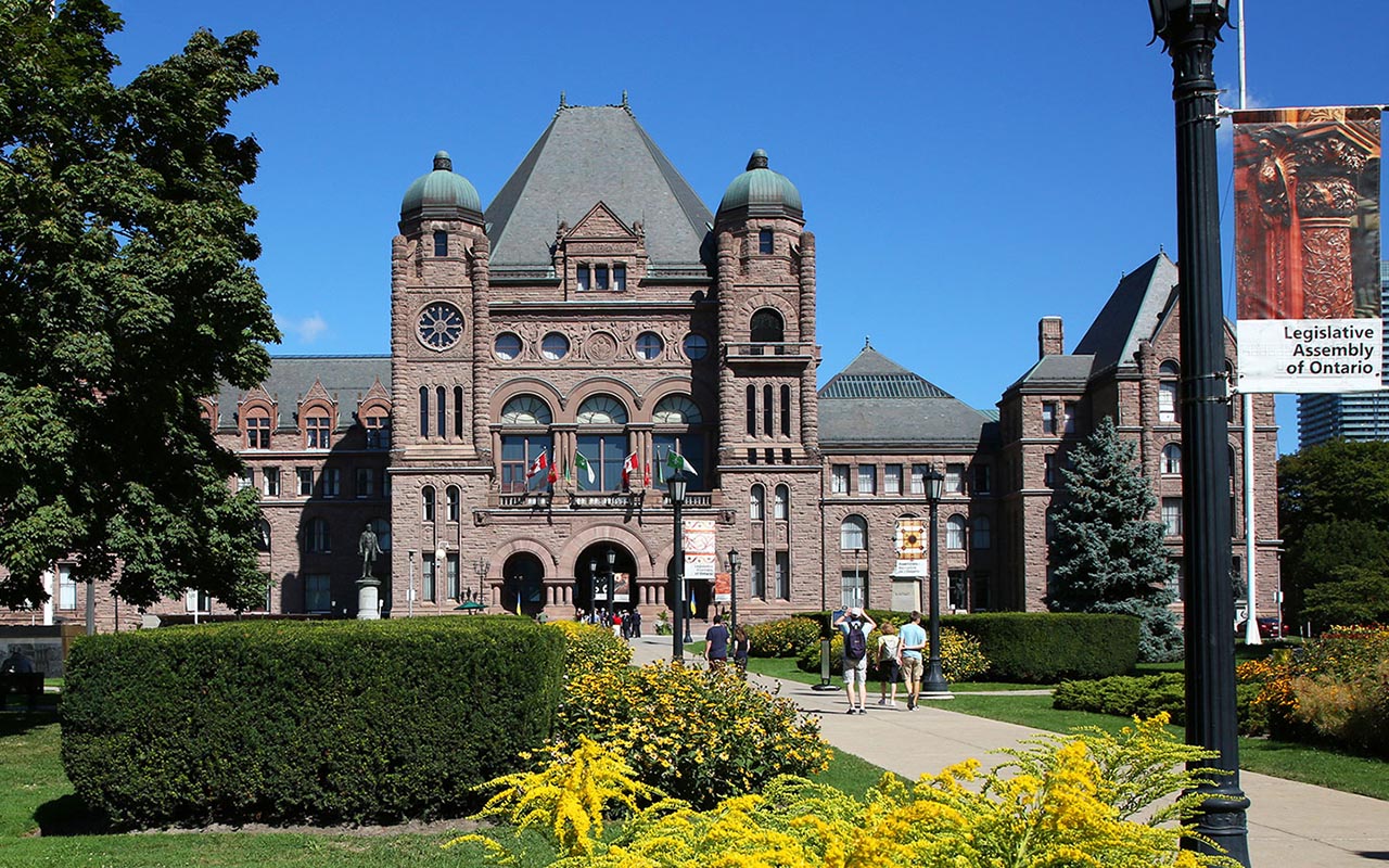 front lawn of Legislative Assembly with trees and buildings in background